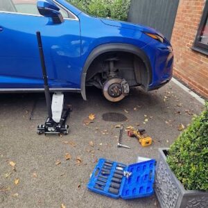 Blue car with wheel removed during mobile tyre replacement